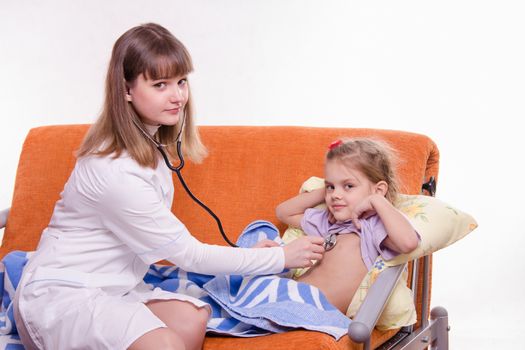 Doctor pediatrician examines a sick child at home