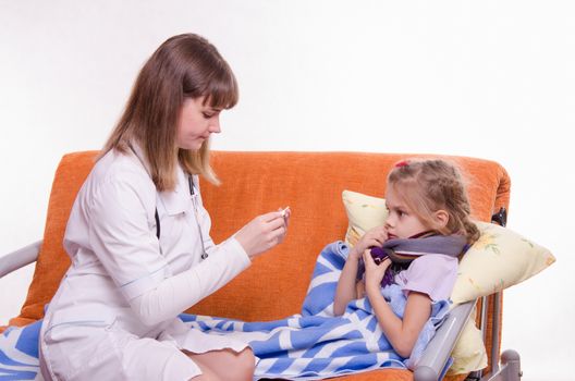 Doctor pediatrician examines a sick child at home