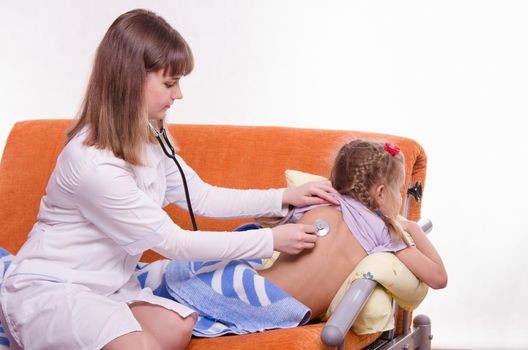 Doctor pediatrician examines a sick child at home