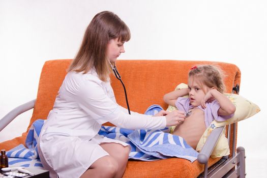 Doctor pediatrician examines a sick child at home