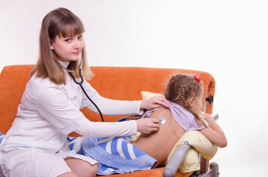 Doctor pediatrician examines a sick child at home