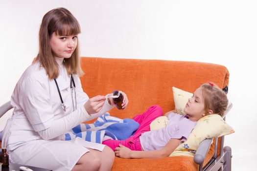 Doctor pediatrician examines a sick child at home