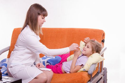 Doctor pediatrician examines a sick child at home