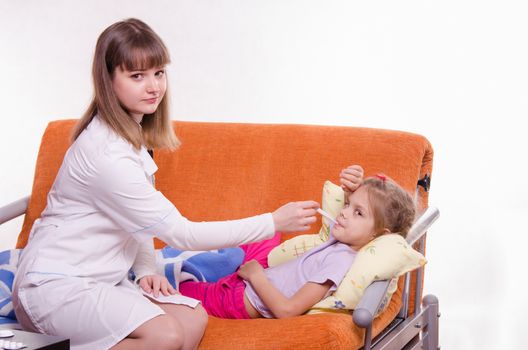 Doctor pediatrician examines a sick child at home