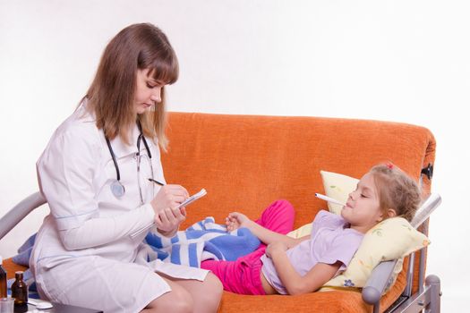 Doctor pediatrician examines a sick child at home