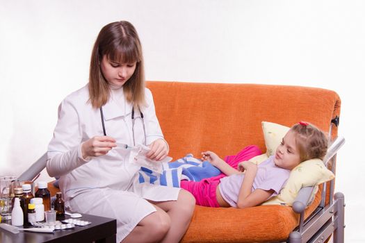 Doctor pediatrician examines a sick child at home
