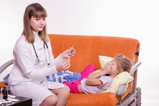 Doctor pediatrician examines a sick child at home