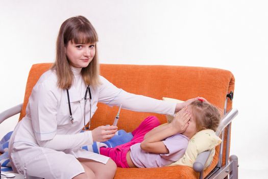 Doctor pediatrician examines a sick child at home