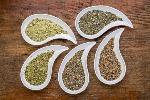 teardrop shaped bowls of seaweed diet supplements (bladderwrack, sea lettuce, kelp, wakame and Irish moss) on a grunge wood background