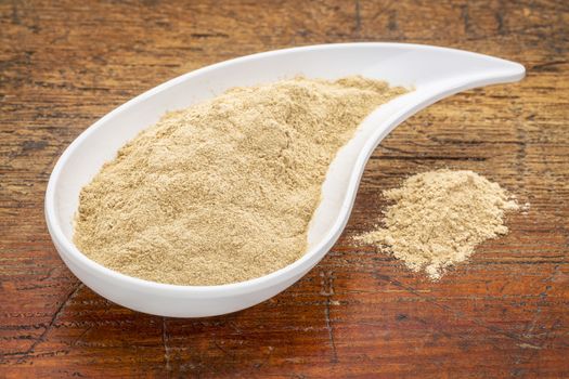 maca root powder in a teardrop shaped bowl against grunge wood