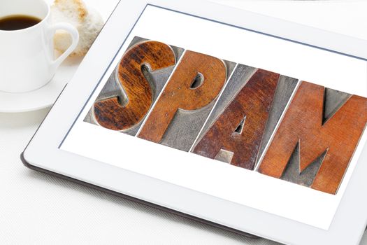 spam  word (unsolicited and unwanted commercial email messages) in letterpress wood type on a digital tablet