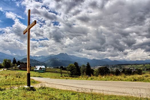 Wooden cross against a blue sky full of clouds