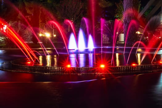 Fountain in night illuminated red, blue and yellow colors