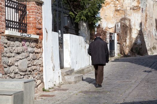 XANTHI, GREECE - FEB 22, 2015: An old man walking in the beautiful old city of Xanthi, Greece