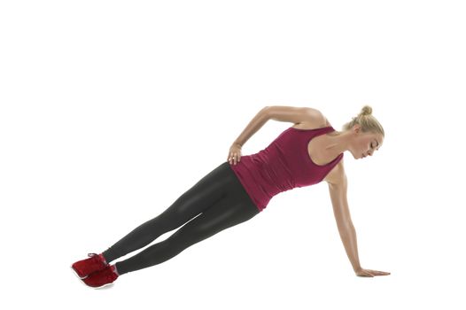 Fit athletic woman working out in a gym balancing at full stretch on her extended arm as she tones her muscles, isolated on white in a health and fitness concept