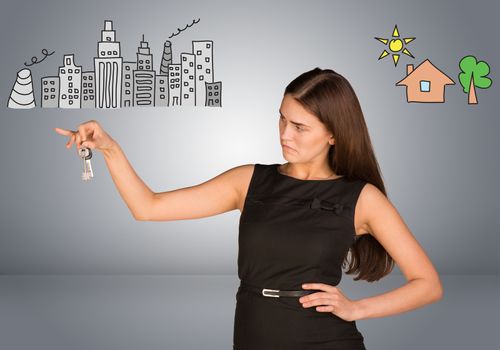 Woman making choice between city and country, looking at keys in her hand, on gray background