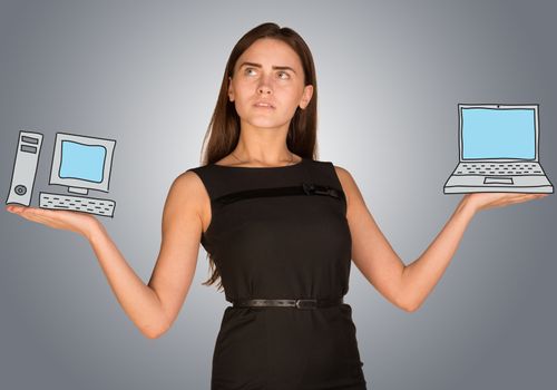 Woman making choice between desktop computer and laptop, on gray background
