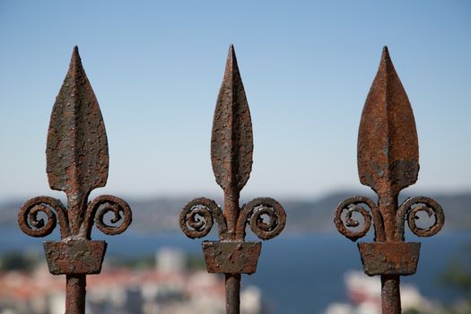 Picture of iron fence tips with a city in the background
