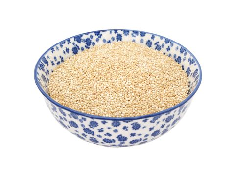 Quinoa in a blue and white porcelain bowl with a floral design, isolated on a white background