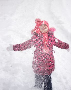 Little girl in winter pink hat in snow.