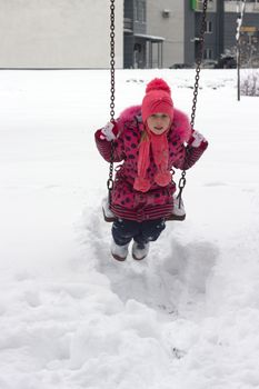 Adorable girl having fun on a swing on beautiful winter day