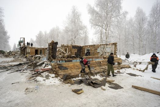 Workers carry timber,dismantle the wall of an old house.