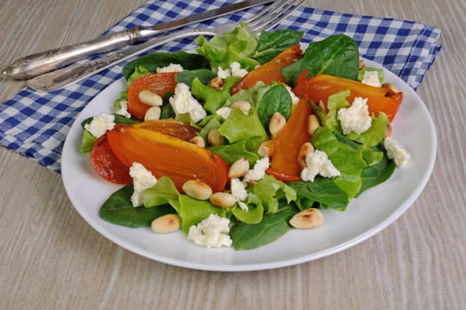 Fresh salad mix with persimmons, feta cheese and peanuts
