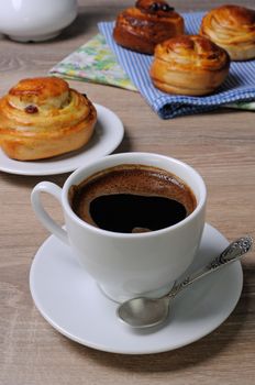 cup of coffee on the table with freshly baked buns with raisins