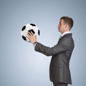 Businessman in suit hold soccer ball. Blue background