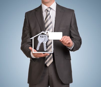 Businessman in suit hold empty card and house icon with keys. Blue background