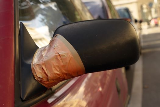 Close up of damaged rearview mirror repaired with scotch