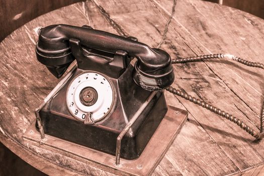 Vintage telephone on old table sepia photo
