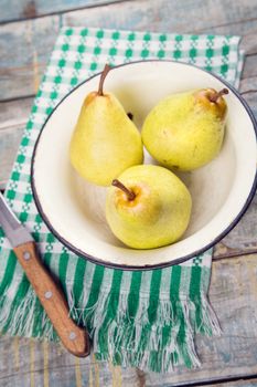 three raw ripe pears in dish on wooden background