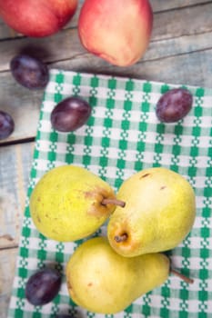 three raw ripe pears,peaches,plums on wooden background in studio