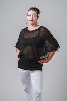 woman in her thirties, wearing a transparent blouse and white pants