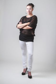 woman in her thirties, wearing a transparent blouse, white pants and high heels