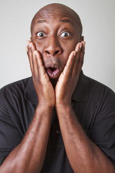 close up portrait of a black man with surprise expression and his hand on his face