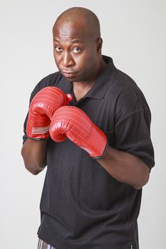 Forty year old black man, wearing a black polo and red boxing glove, holding his arm up in guard position