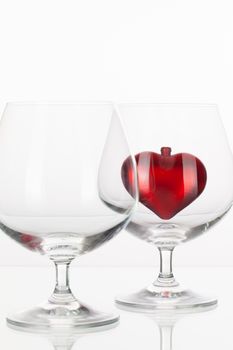 Red heart inside a glass of cognac on a glass plate