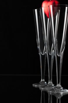 Three champagne glasses and red heart on a glass plate
