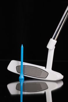 Golf putter and different golf equipments on the black glass desk