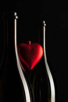 Silhouettes of elegant wine bottles with red heart on a black background