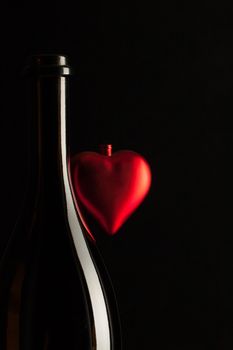 Silhouettes of elegant wine bottles with red heart on a black background