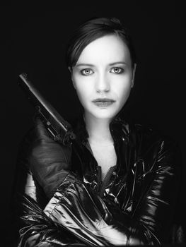 Black and white image of secret agent woman with gun in hand on black background