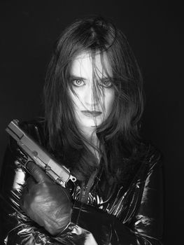 Black and white image of secret agent woman with gun in hand on black background