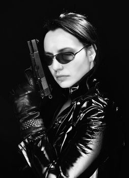 Black and white image of secret agent woman with gun in hand on black background