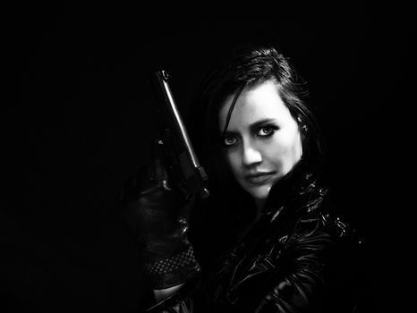 Black and white image of secret agent woman with gun in hand on black background