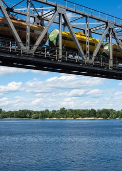 The span of the railroad bridge across the Dnieper in Kyiv. Freight train passing across the bridge.