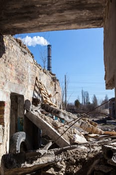 The old ruined brick building. Piles of construction debris. Smoke stack in the background.