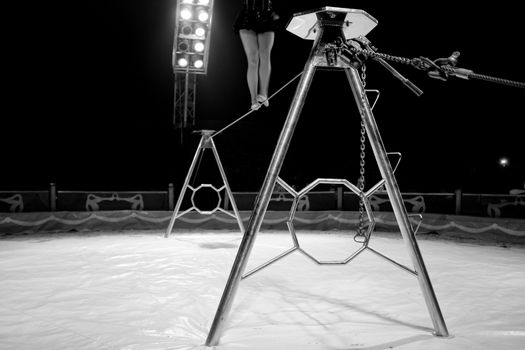 Black and white image of Female acrobat legs performing on horizontal bar